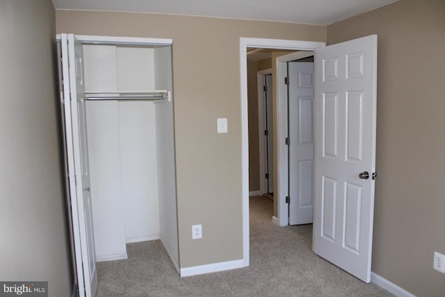 unfurnished bedroom with light carpet and a closet