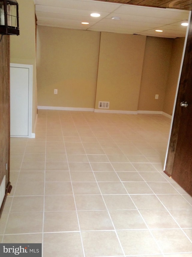 basement featuring a paneled ceiling and light tile patterned floors