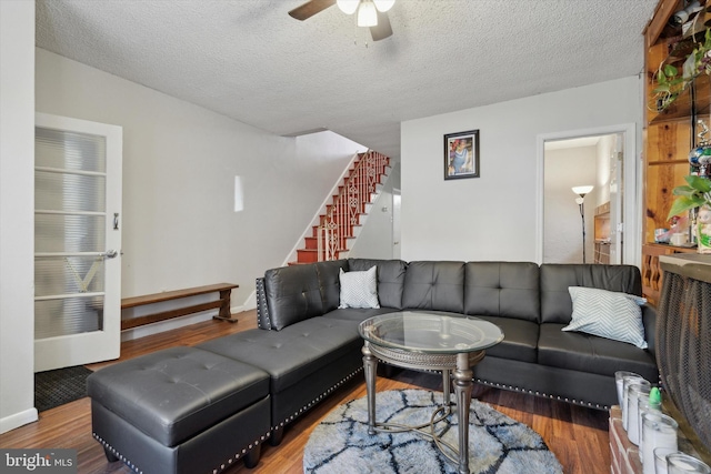 living room featuring ceiling fan, hardwood / wood-style floors, and a textured ceiling