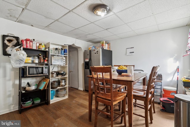 dining room with a drop ceiling and dark wood-type flooring