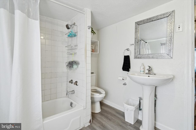 full bathroom with shower / tub combo with curtain, sink, hardwood / wood-style flooring, a textured ceiling, and toilet