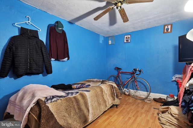 bedroom with ceiling fan, hardwood / wood-style floors, and a textured ceiling