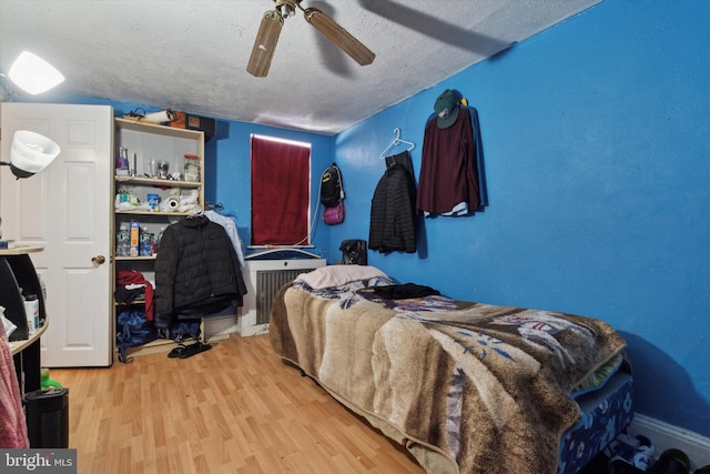 bedroom with a textured ceiling, light hardwood / wood-style flooring, and ceiling fan