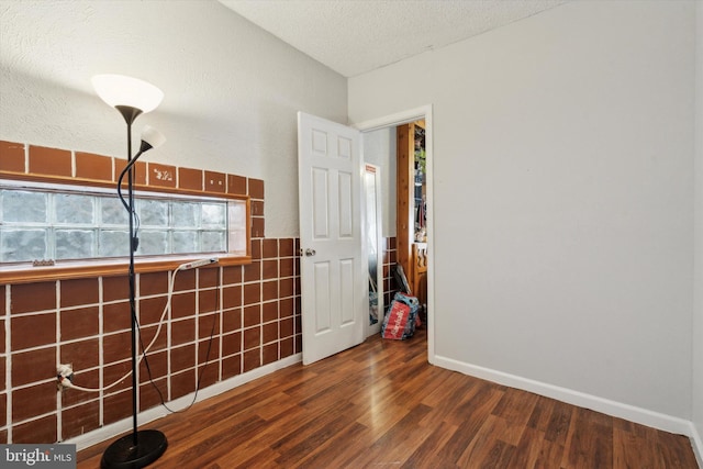 unfurnished room with a textured ceiling and dark hardwood / wood-style flooring