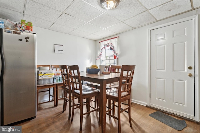 dining area with a drop ceiling and hardwood / wood-style floors