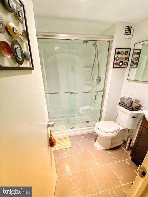 bathroom with vanity, toilet, tile patterned floors, and a shower with shower door