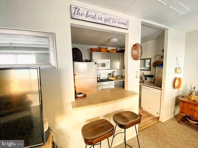 kitchen featuring white appliances and a kitchen breakfast bar