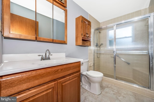 bathroom with vanity, a shower with door, and toilet