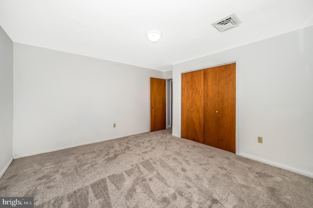 unfurnished bedroom featuring light carpet and a closet