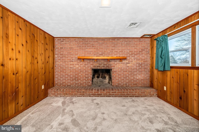 unfurnished living room featuring a brick fireplace, light carpet, and wood walls