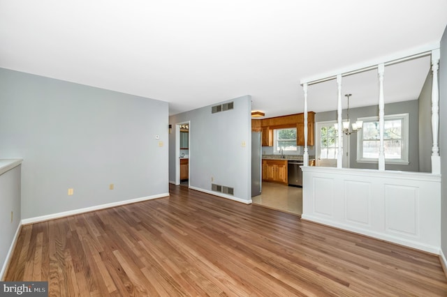 unfurnished living room featuring light hardwood / wood-style flooring and a chandelier