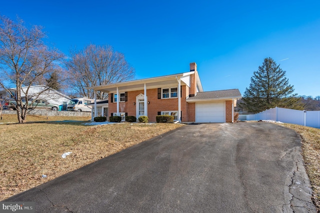 raised ranch featuring a garage and a front lawn