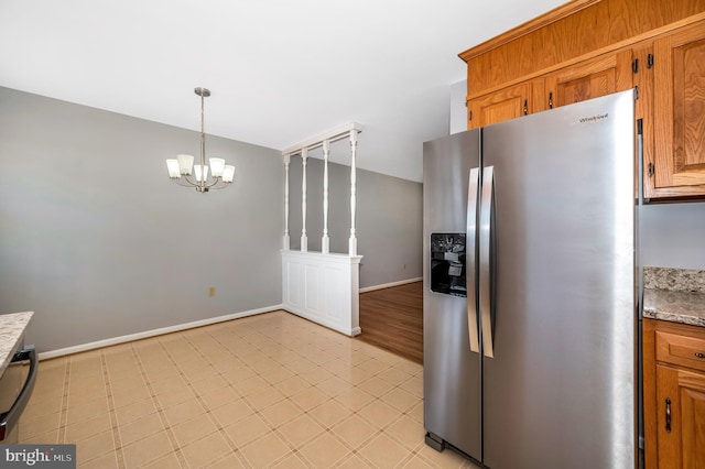 kitchen featuring stainless steel refrigerator with ice dispenser, light stone counters, a chandelier, dishwasher, and pendant lighting