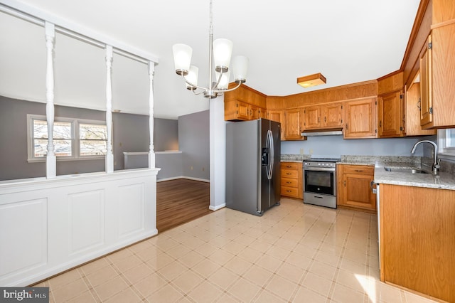 kitchen featuring sink, a chandelier, hanging light fixtures, light stone counters, and stainless steel appliances