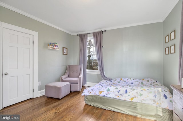 bedroom featuring baseboards, wood finished floors, and crown molding