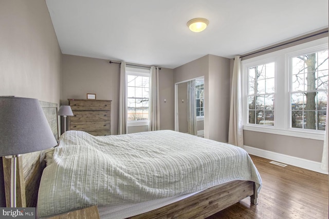 bedroom with baseboards, visible vents, and wood finished floors