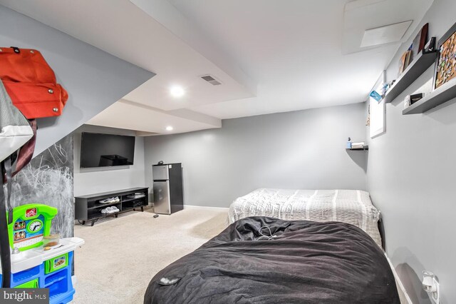 carpeted bedroom with visible vents and freestanding refrigerator