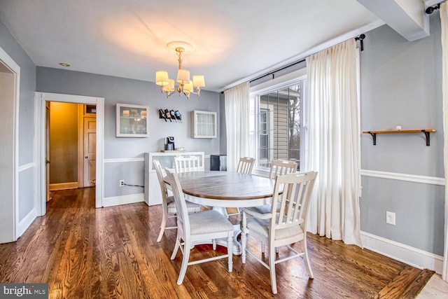 dining space featuring baseboards, dark wood finished floors, and an inviting chandelier