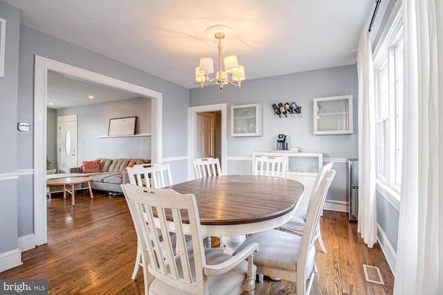 dining area featuring a chandelier, wood finished floors, visible vents, and baseboards