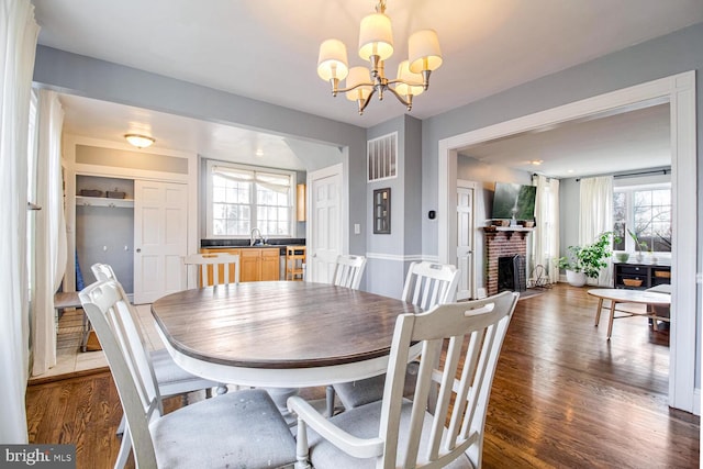 dining space with dark wood-type flooring, a notable chandelier, and a fireplace