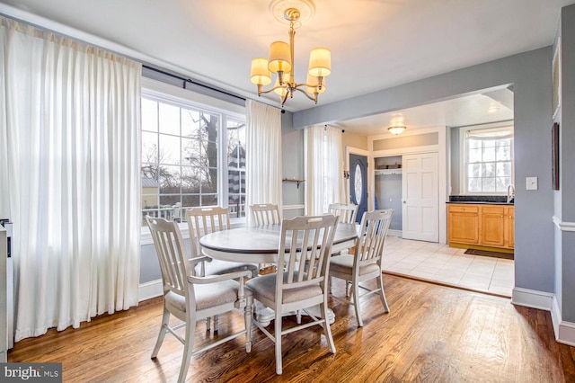 dining area featuring light wood-style flooring, baseboards, and a notable chandelier