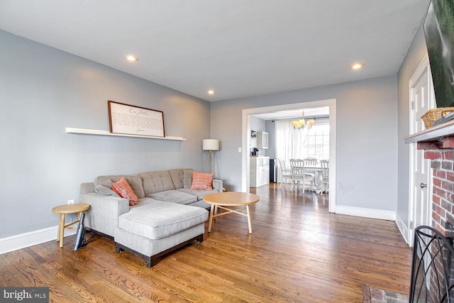 living area featuring a brick fireplace, baseboards, wood finished floors, and recessed lighting