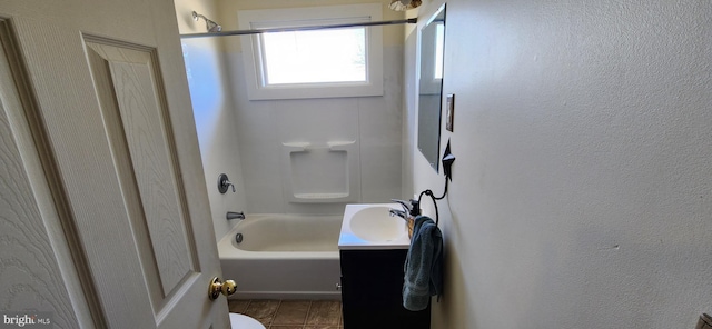 bathroom with toilet, a textured wall, washtub / shower combination, and vanity