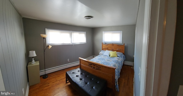 bedroom featuring a baseboard heating unit and wood finished floors