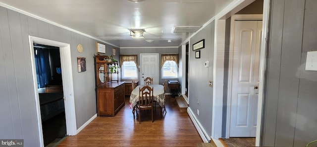 dining room featuring a baseboard heating unit, dark wood-style flooring, visible vents, baseboards, and ornamental molding