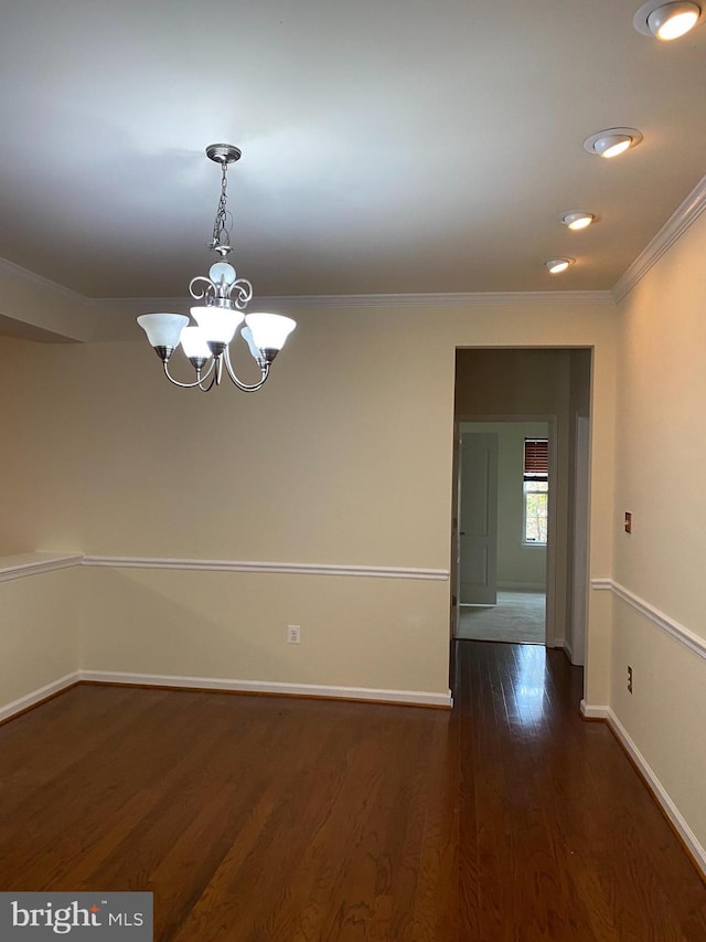 empty room featuring an inviting chandelier, dark wood-type flooring, and ornamental molding