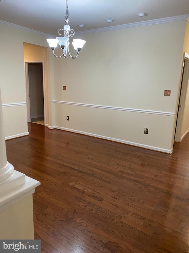 unfurnished room featuring an inviting chandelier, dark hardwood / wood-style flooring, ornamental molding, and ornate columns