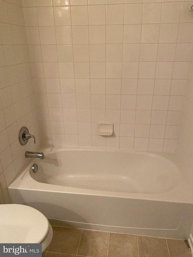 bathroom with bathing tub / shower combination, tile patterned floors, and toilet