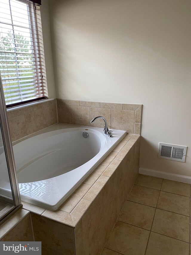 bathroom with tile patterned flooring and tiled bath