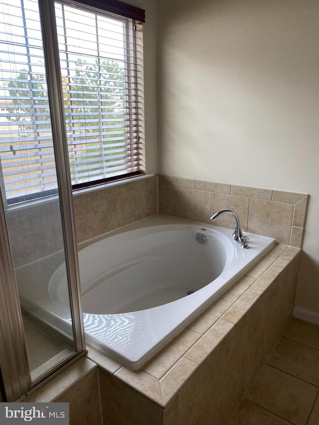 bathroom featuring tiled tub, a wealth of natural light, and tile patterned floors