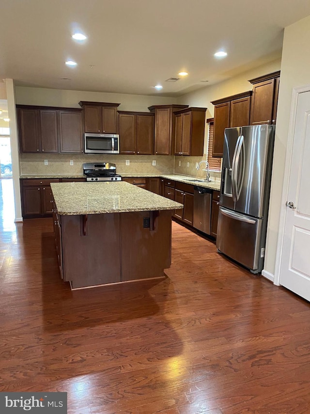 kitchen featuring sink, a breakfast bar, stainless steel appliances, tasteful backsplash, and a kitchen island