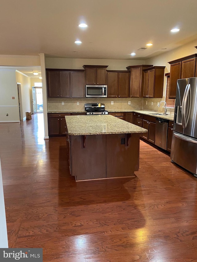 kitchen with a breakfast bar, sink, backsplash, a center island, and stainless steel appliances