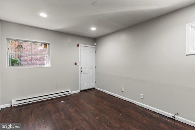 empty room with dark wood-type flooring and a baseboard radiator