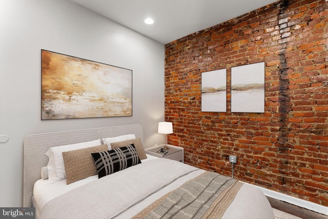 bedroom with wood-type flooring and brick wall