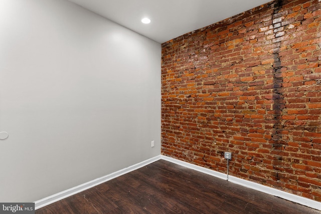 spare room with hardwood / wood-style flooring and brick wall