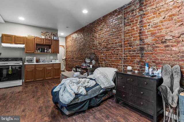 kitchen featuring dark wood-type flooring, brick wall, and electric range