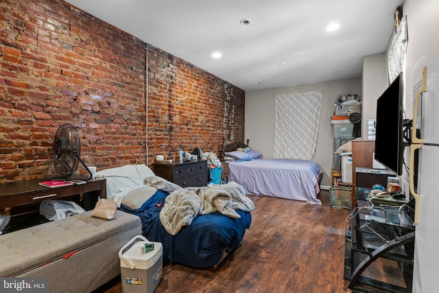 bedroom with brick wall and dark hardwood / wood-style flooring