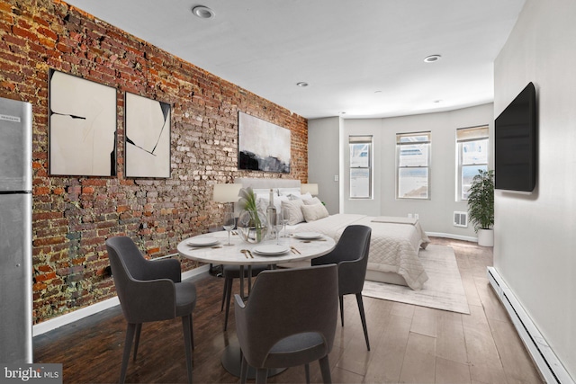 dining space with hardwood / wood-style flooring, a baseboard radiator, and brick wall