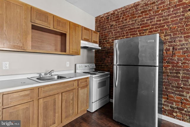 kitchen with dark wood-type flooring, white electric range oven, sink, stainless steel refrigerator, and brick wall