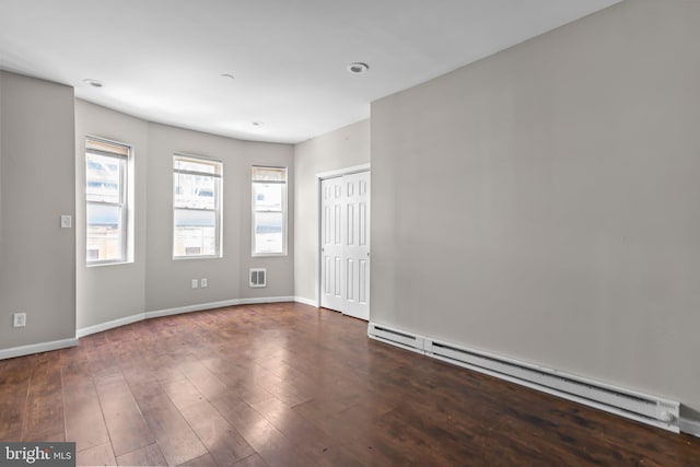 unfurnished room featuring a baseboard radiator and dark hardwood / wood-style floors