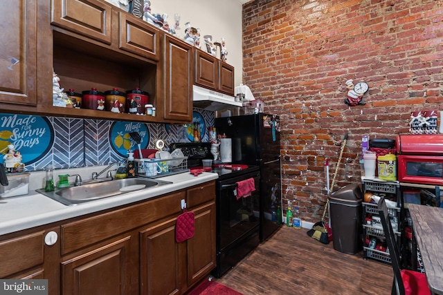 kitchen featuring black electric range oven, sink, dark wood-type flooring, tasteful backsplash, and brick wall