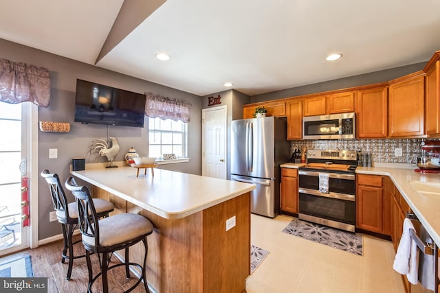 kitchen featuring lofted ceiling, a breakfast bar, sink, appliances with stainless steel finishes, and backsplash