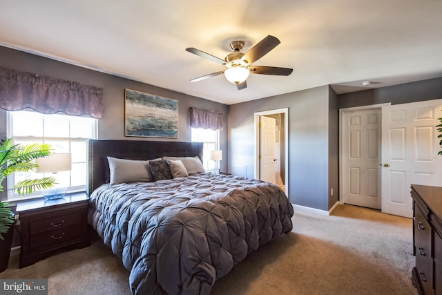 bedroom with ensuite bath, light colored carpet, and ceiling fan