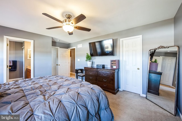 bedroom with connected bathroom, light colored carpet, and ceiling fan