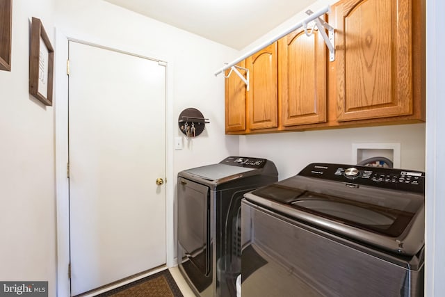 clothes washing area featuring cabinets and washer and dryer