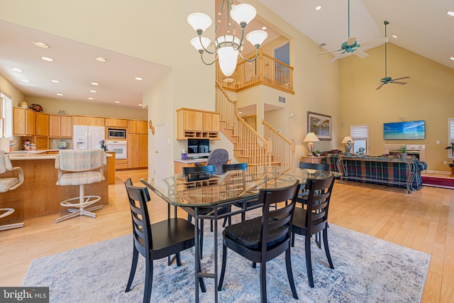 dining room featuring high vaulted ceiling, light hardwood / wood-style floors, and a notable chandelier